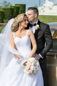 Groom kissing bride in white wedding gown