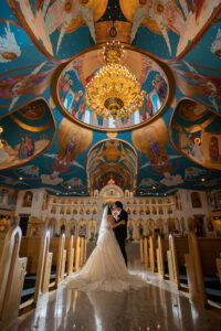 Wedding couple kissing under ornate church chandelier